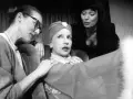 Marlena Milwiw młoda, w otoczeniu dwóch kobiet, w teatralnej scenie.