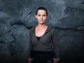 Natalia Brudniak w wojskowym stylu, z rękami w kieszeniach, na tle zniszczonej ściany.