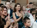 Agnieszka Grochowska z uśmiechem klaszcze, otoczona ludźmi na widowni.