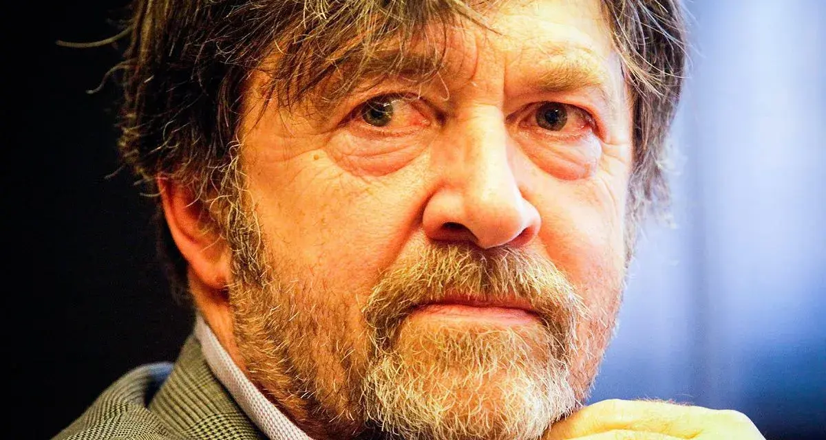 Zbliżenie na twarz Olek Krupa, z siwiejącą brodą i zmarszczkami wokół oczu.
