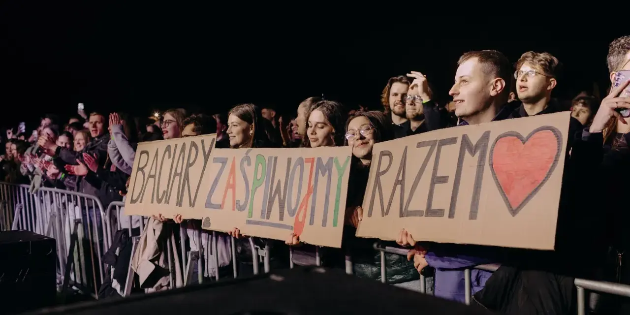 Fani trzymają transparent: "Baciary zaśpiewajmy razem" z sercem.