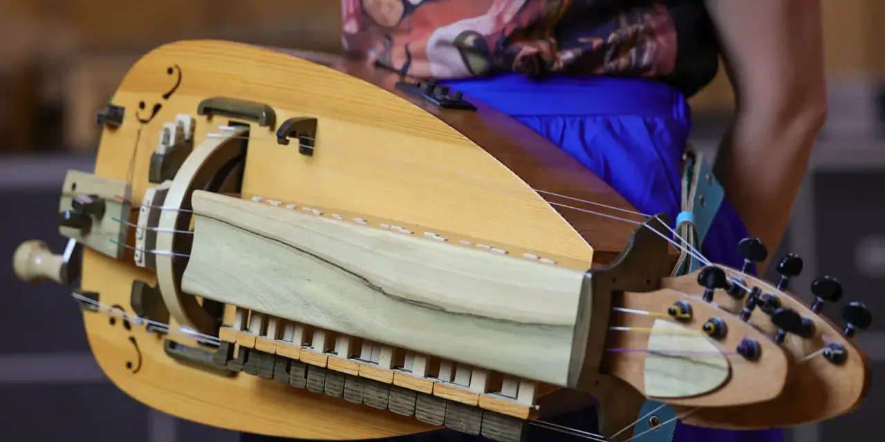 Drewniana lira korbowa, kozacki instrument muzyczny, z widocznymi strunami, klawiszami i korbą.