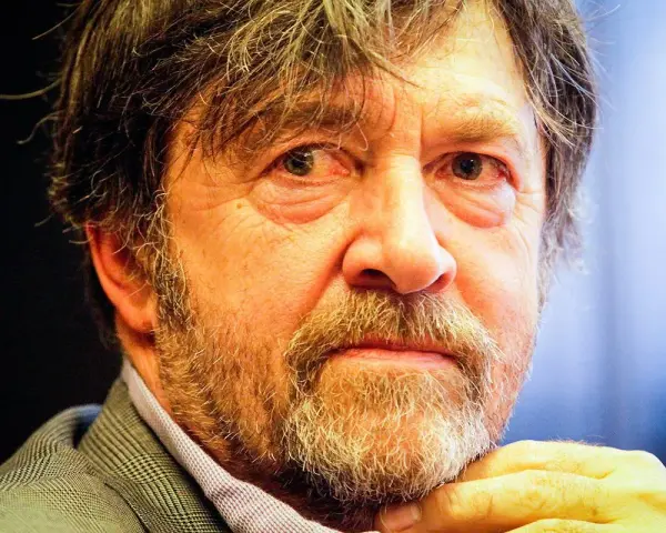 Zbliżenie na twarz Olek Krupa, z siwiejącą brodą i zmarszczkami wokół oczu.