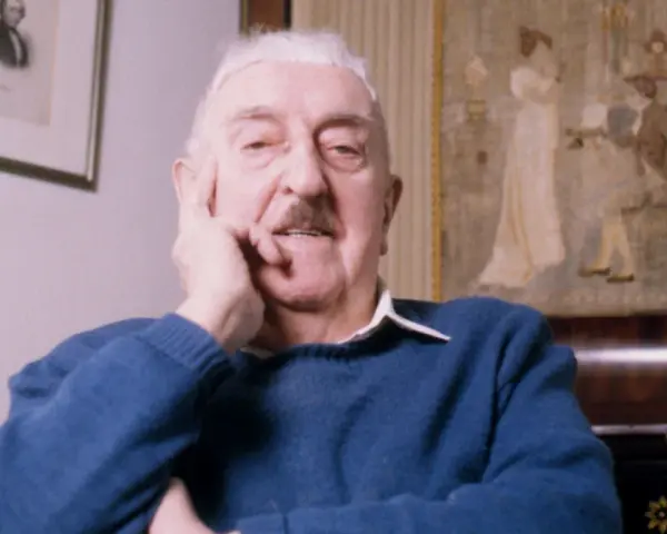 Jerzy Waldorff, znany z zamiłowania do kultury i sztuki, w niebieskim swetrze. Jego wykształcenie i pasje widoczne w tle.