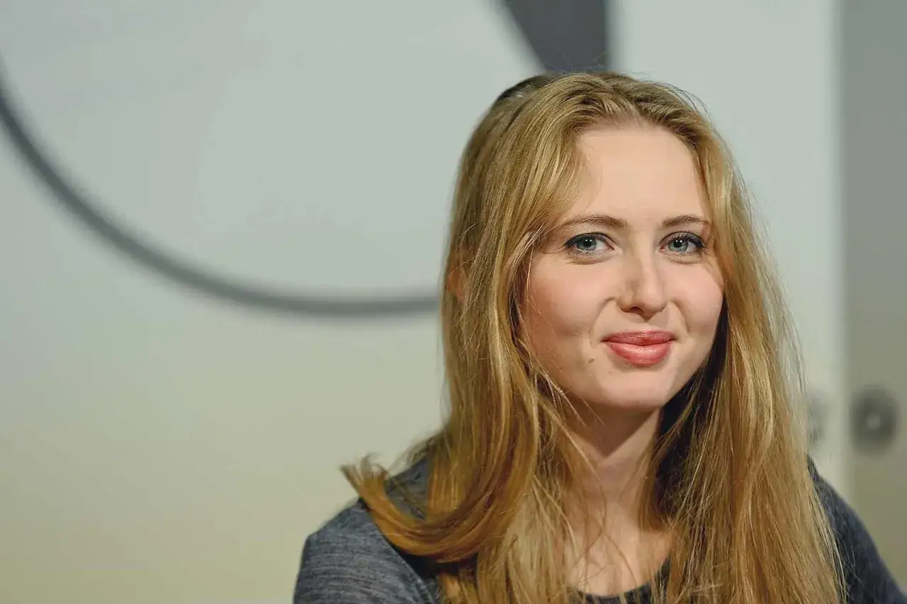 Uśmiechnięta Justyna Wasilewska z długimi blond włosami, patrzy w obiektyw.