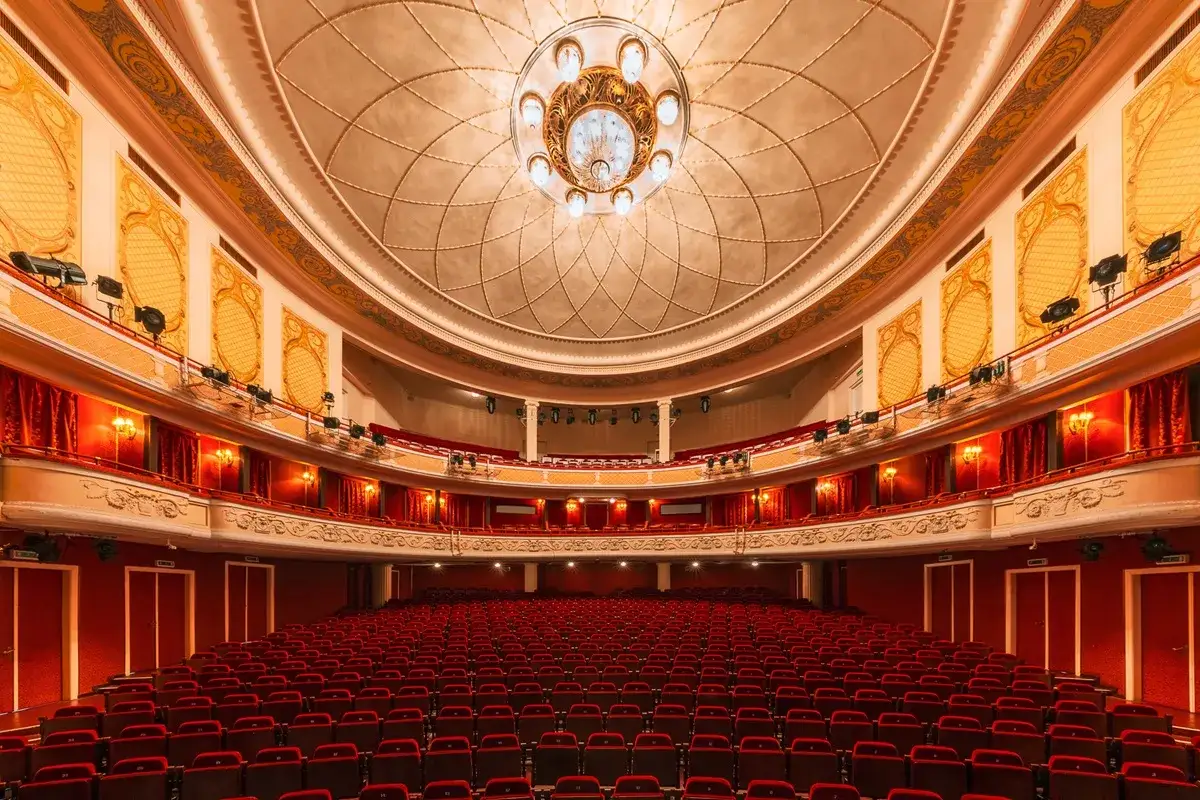 Wnętrze teatru z rzędami czerwonych foteli i bogato zdobionym sufitem. Może tu odbyć się wesele w teatrze polskim.