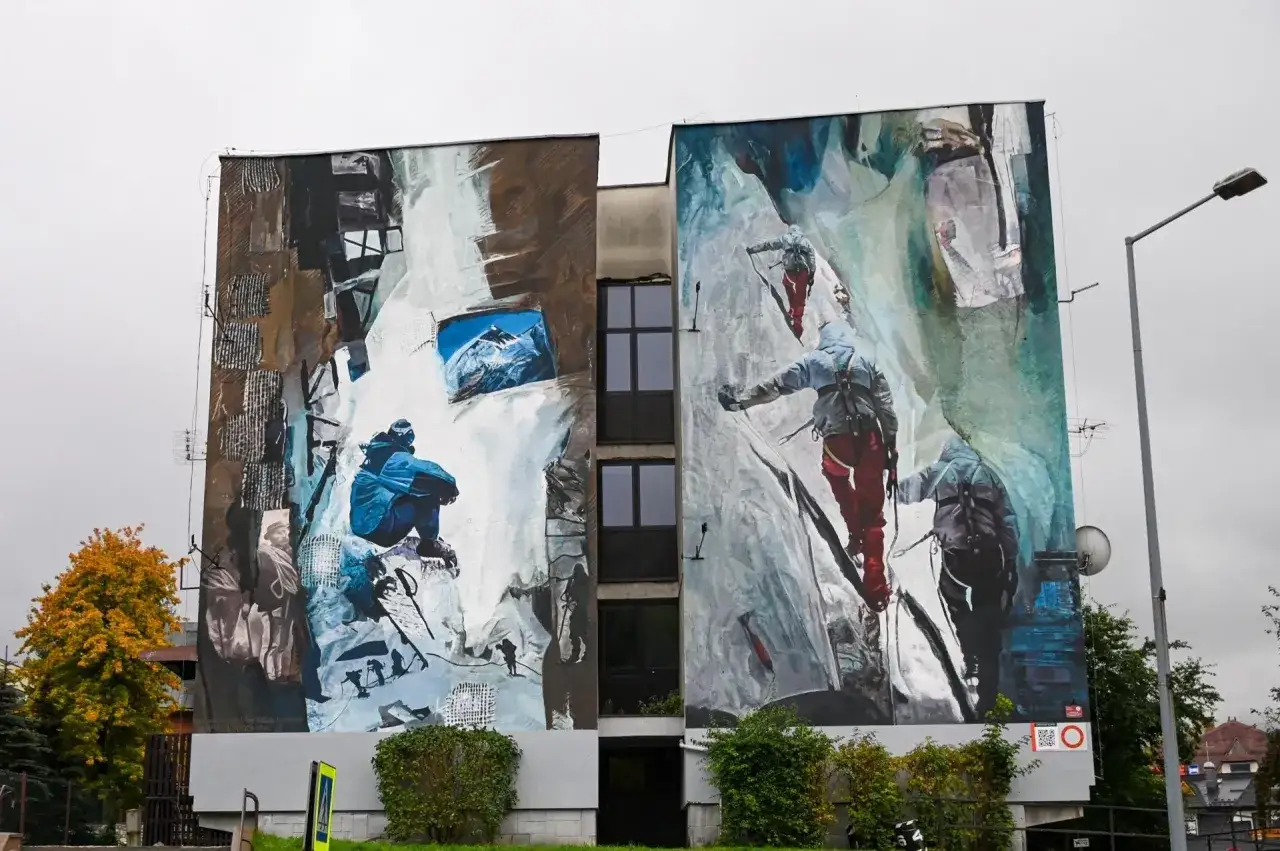 Mural Ewy Berbeki na bloku: wspinacze na skalnej ścianie i siedząca postać.