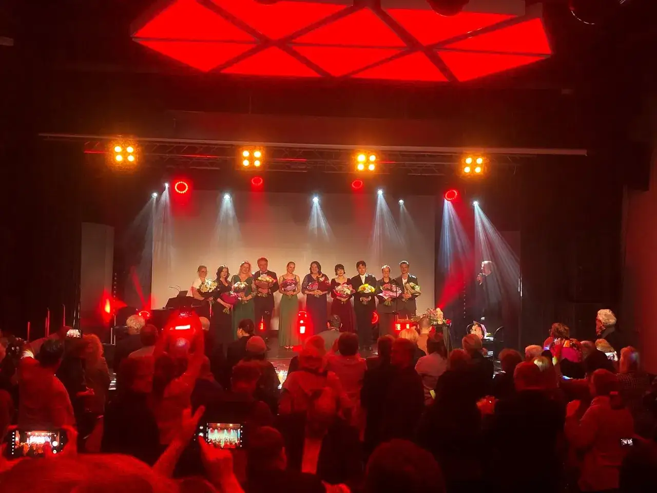 Na scenie Dariusz Paradowski i inni artyści odbierają kwiaty od publiczności.