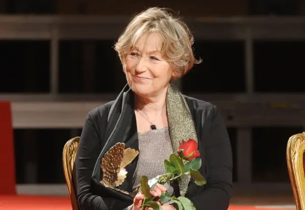 Teresa Budzisz-Krzyżanowska z mężem na scenie, trzymająca czerwoną różę i statuetkę.