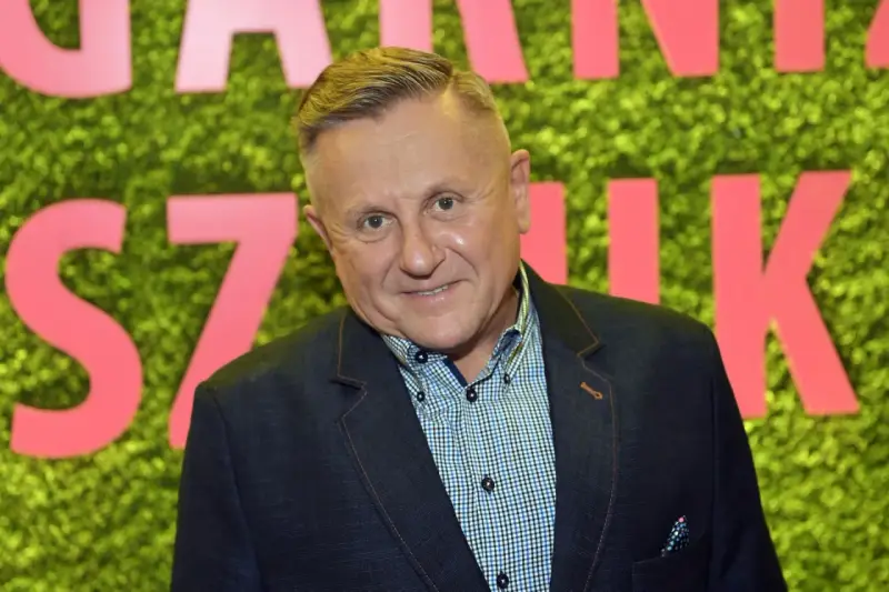 Krzysztof Hanke w garniturze, uśmiecha się. Może właśnie wraca do żony po udanym dniu.